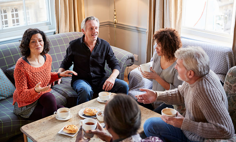 Middle aged friends having tea in a lounge room