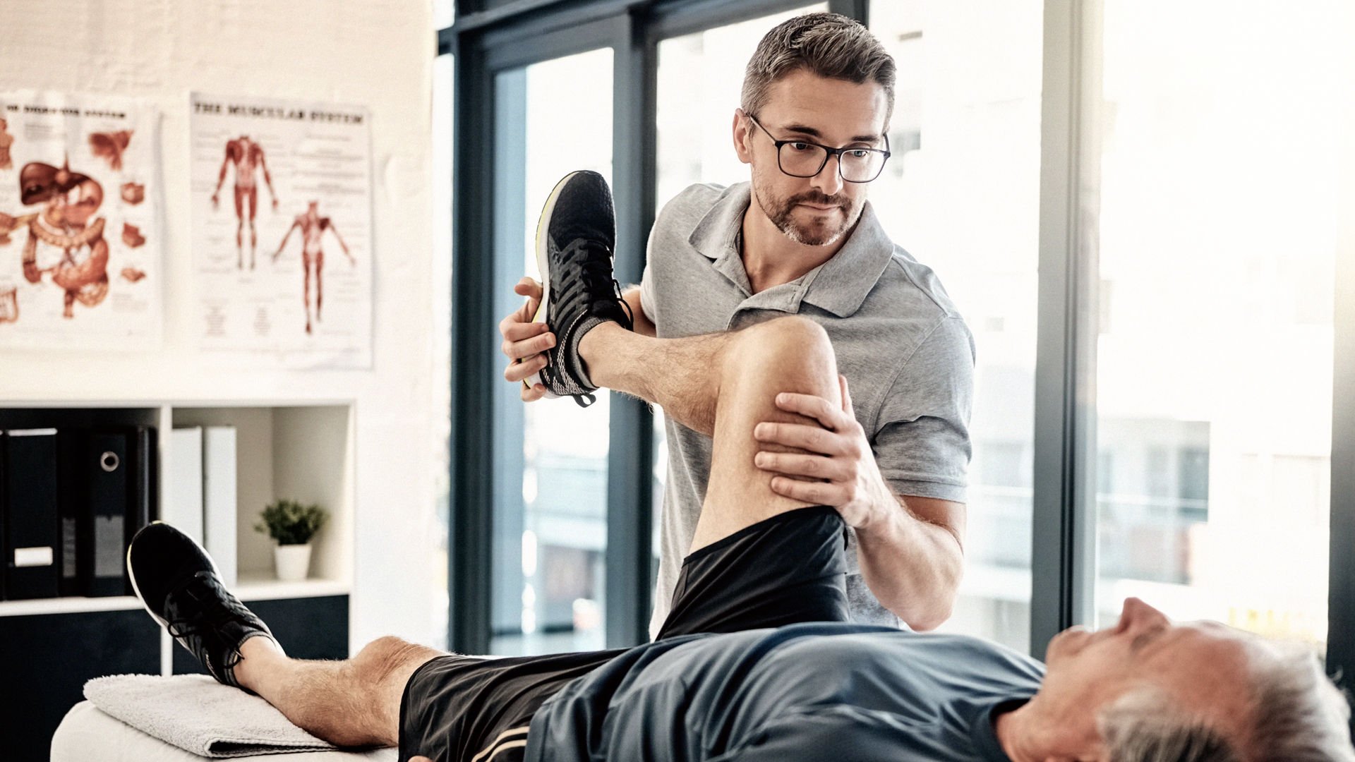male physio helping older man with knee pain