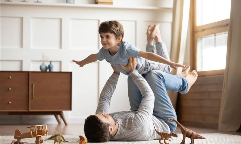 Father and son playing on the floor with toys