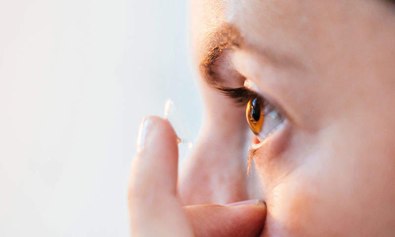 A person putting a contact lens in their eye