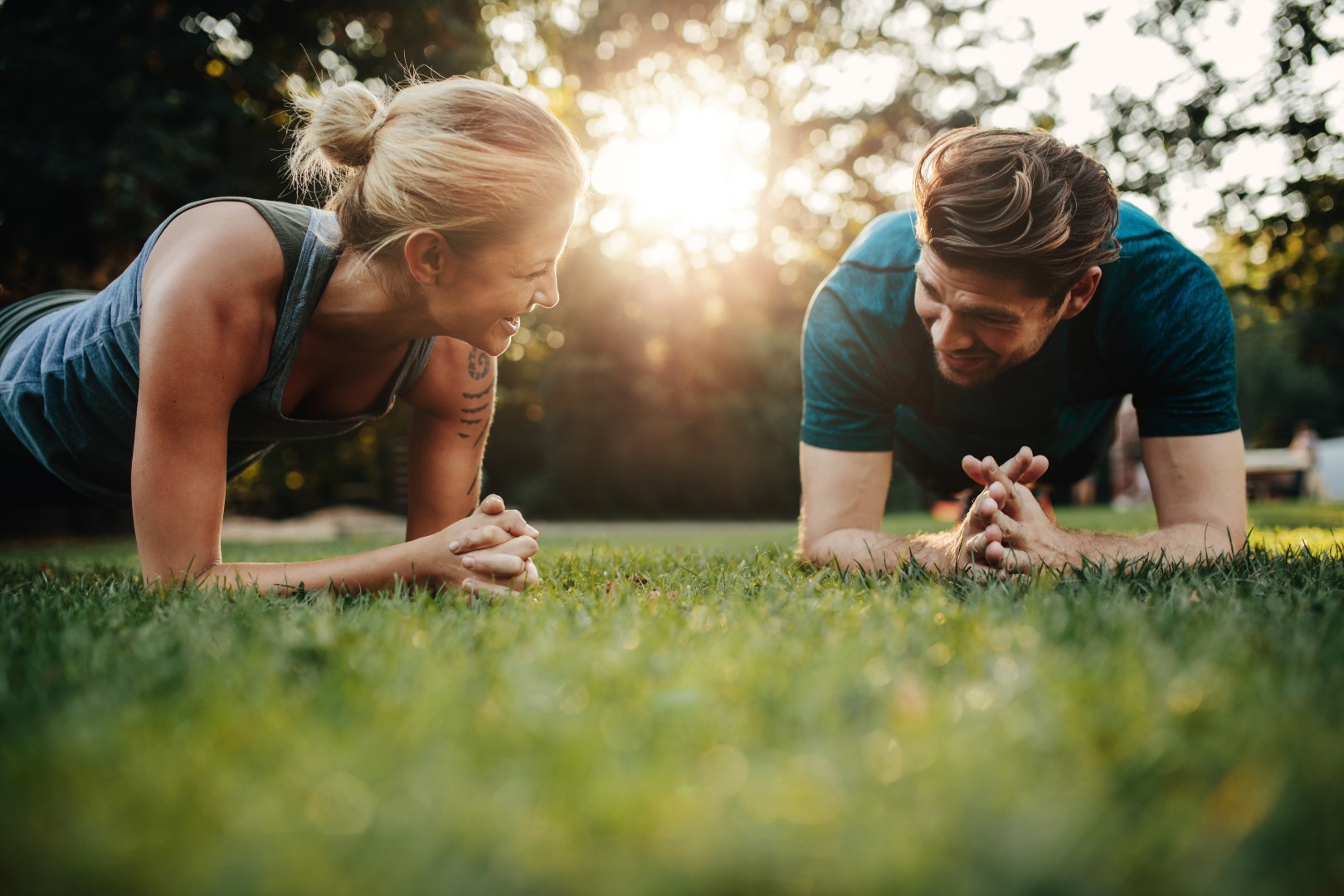 Young couple do a plank in the park, trying to build their AIA Vitality points through their GMHBA insurance