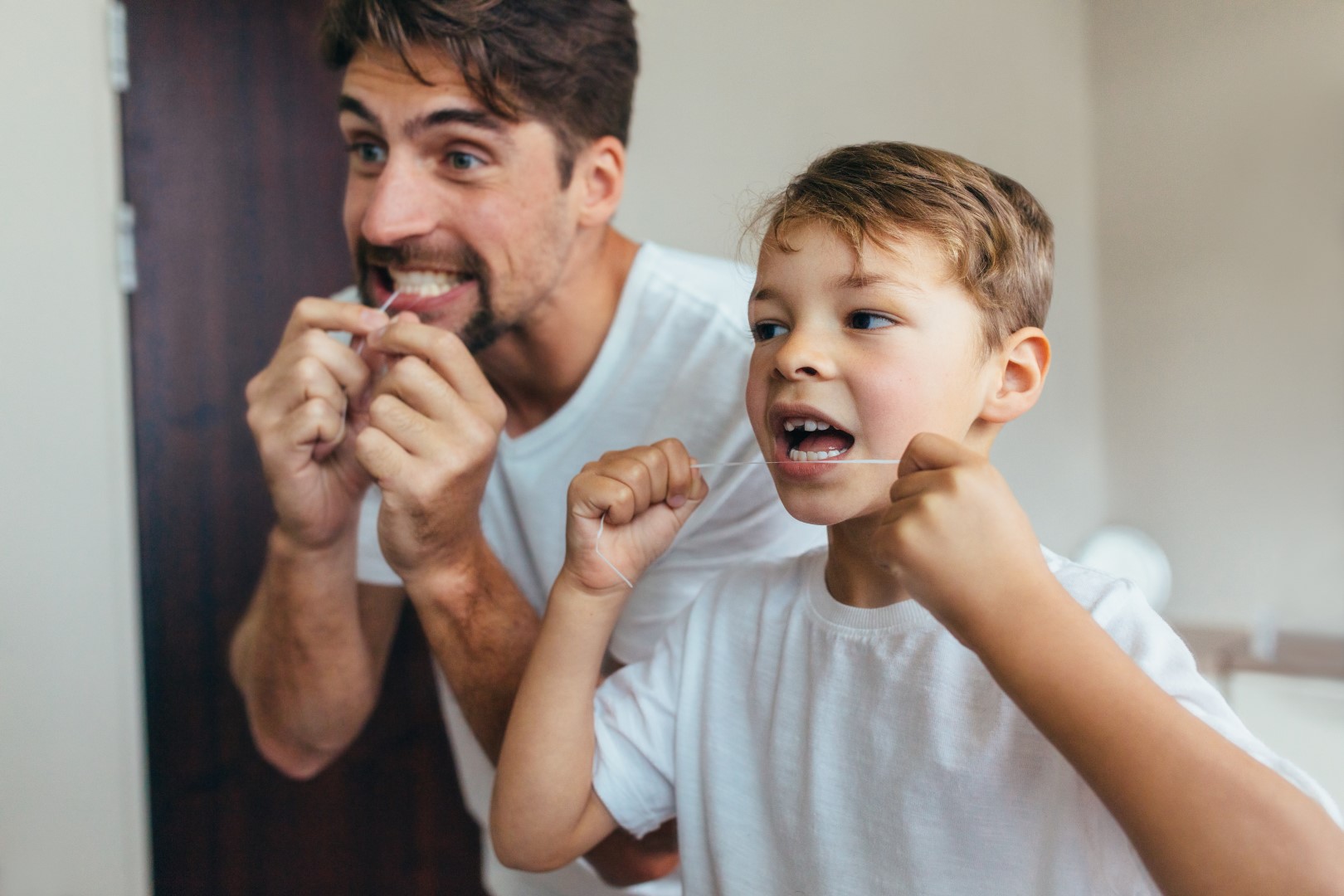 Father and son flossing together after visiting the GMHBA Dental Care practice
