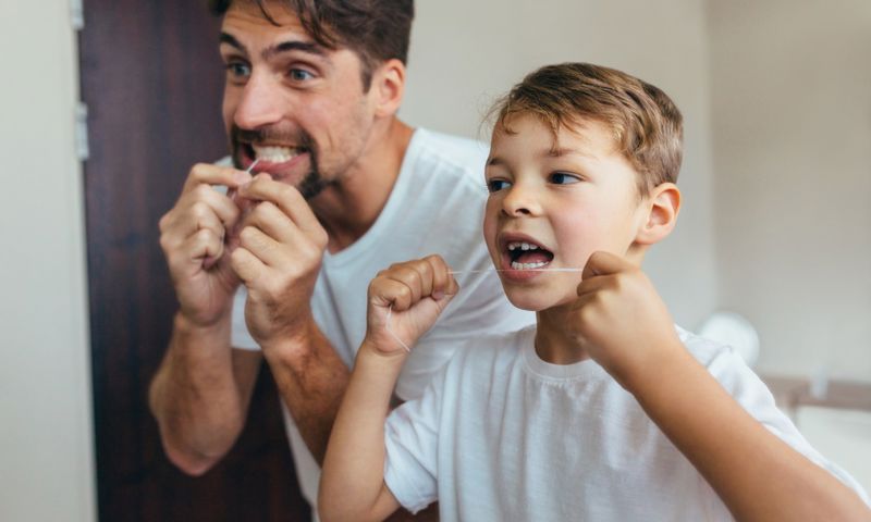 GMHBA member and son flossing their teeth after a dental visit with a smile.com.au registered dentist