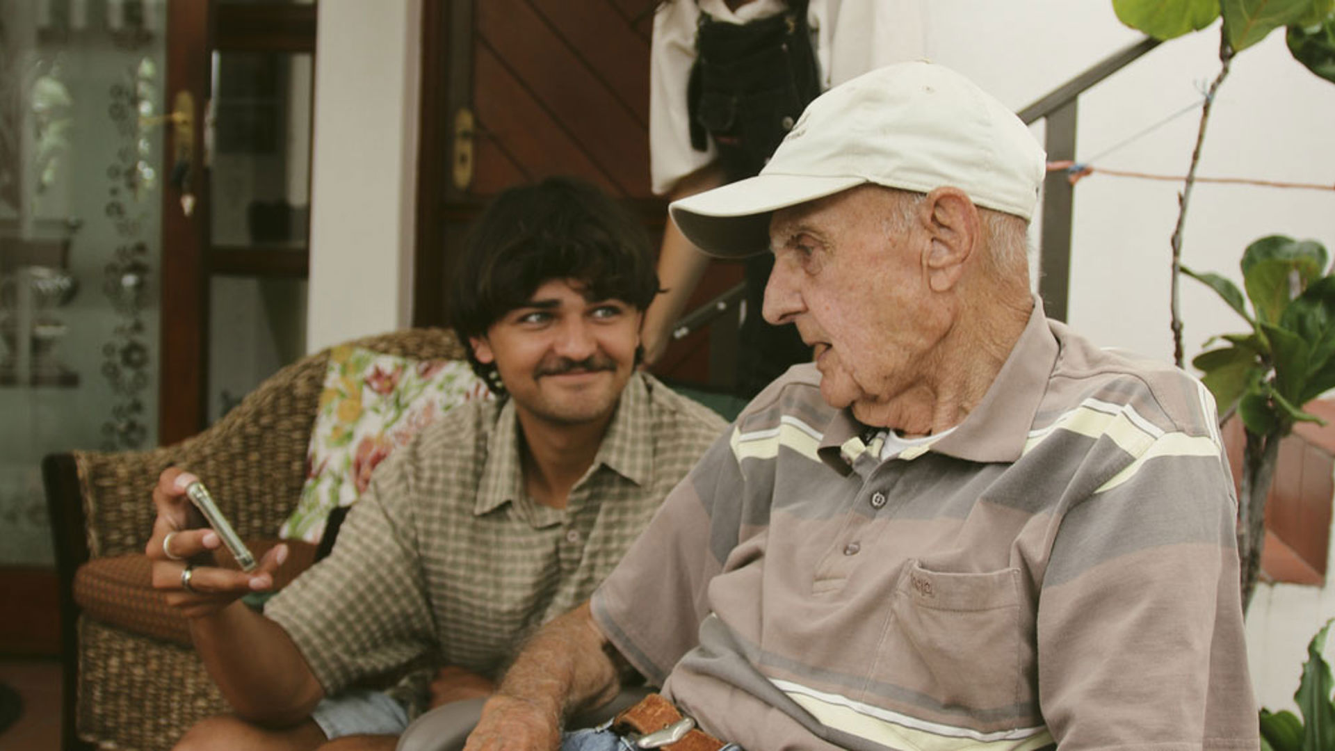 Old man on the couch watching a young persons phone