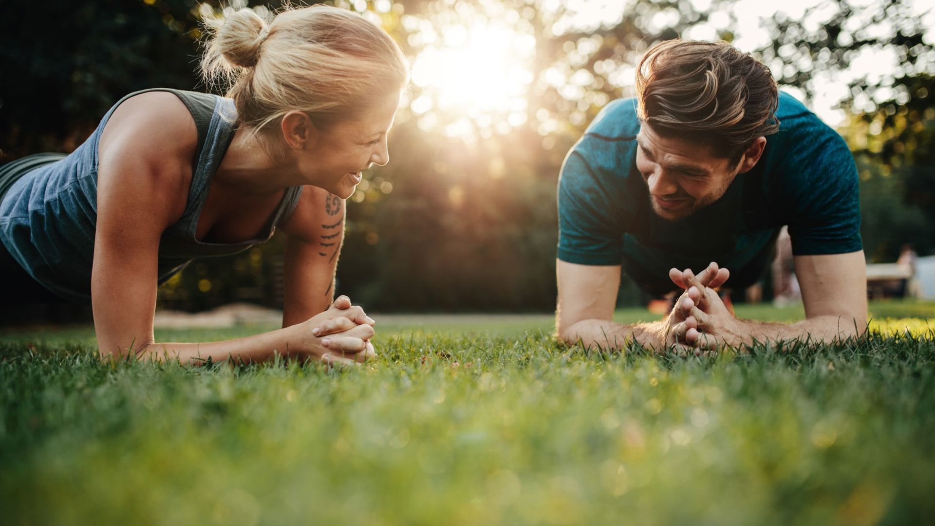 Young couple do a plank in the park, trying to build their AIA Vitality points through their GMHBA insurance
