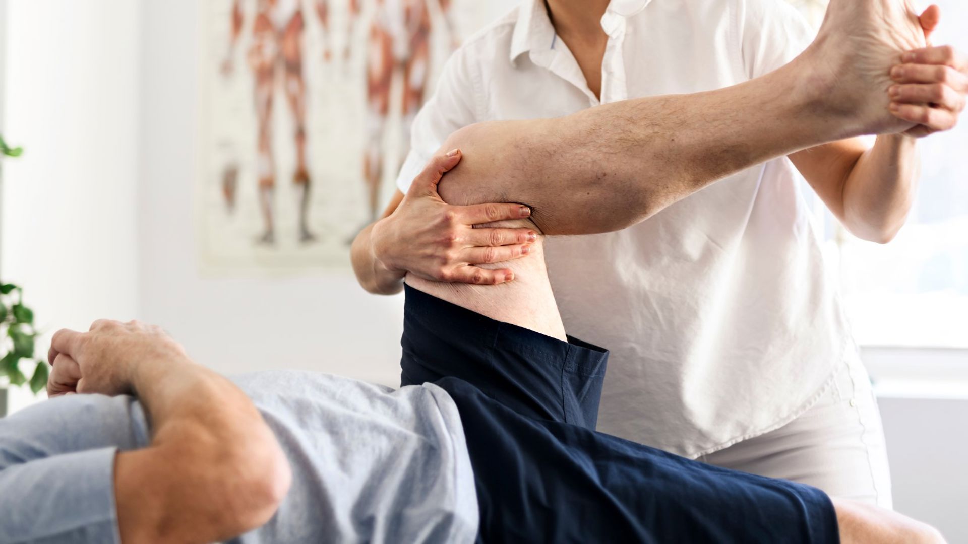 Man lying on back with the physio holding his knee and rotating