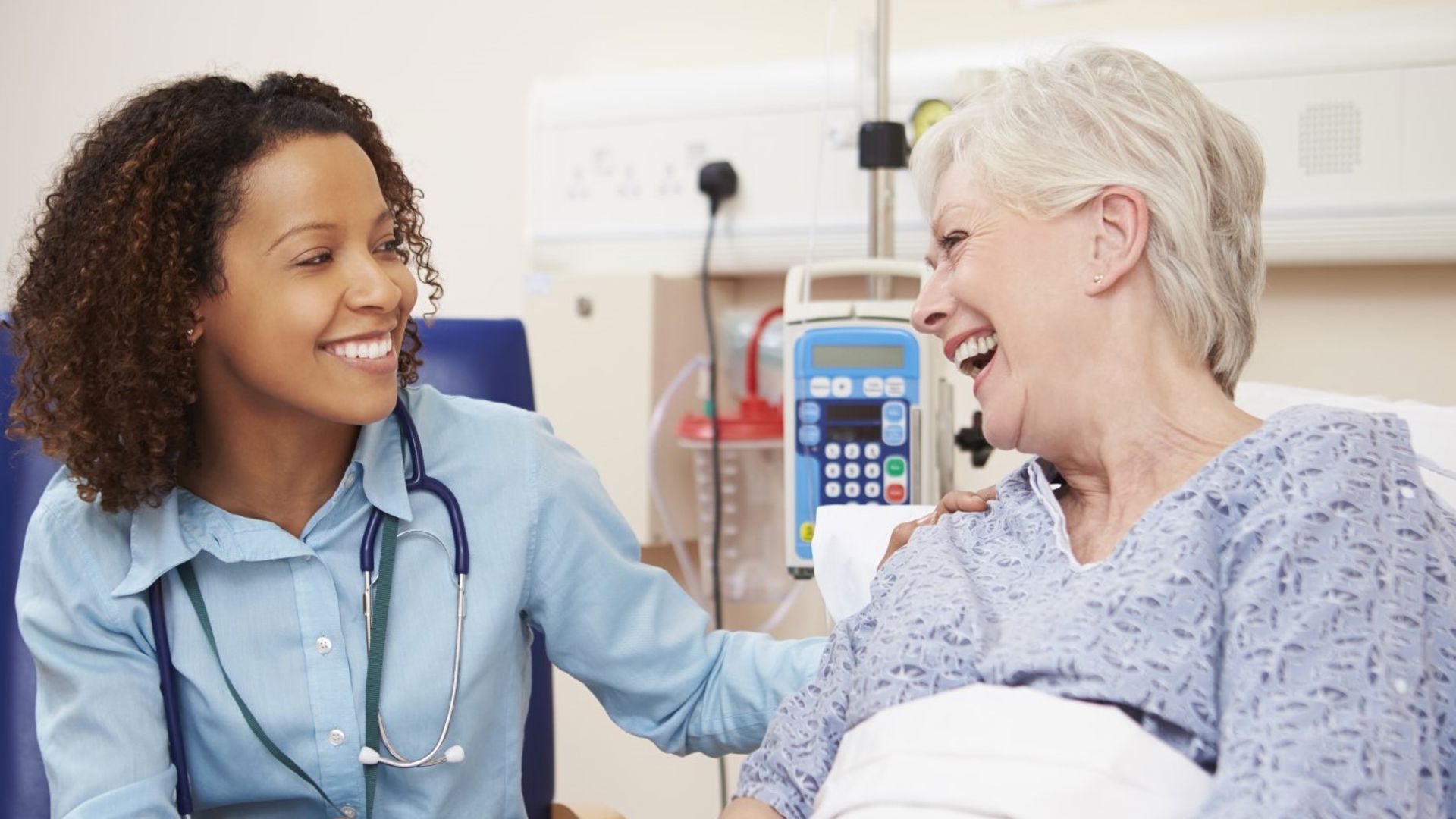 Older lady in hospital bed sitting with nurse