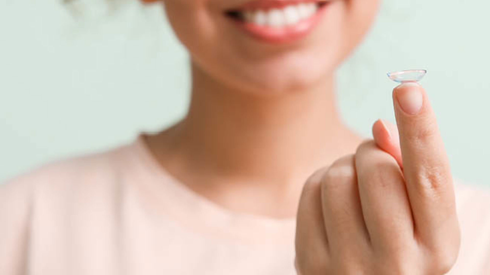 Curly hair lady with a contact lens on her finger