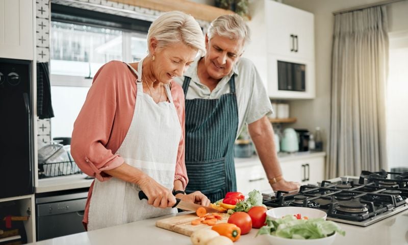 Ageing couple in kitchen cooking vegetables to make a healthy meal