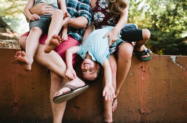 Parents dangling and tickling kid