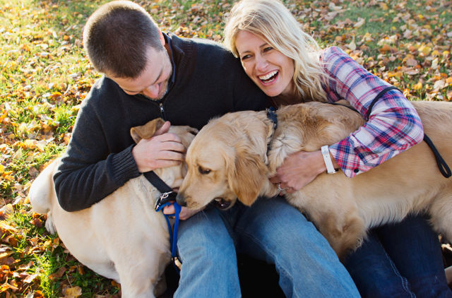 Couple cuddling their dog on the ground
