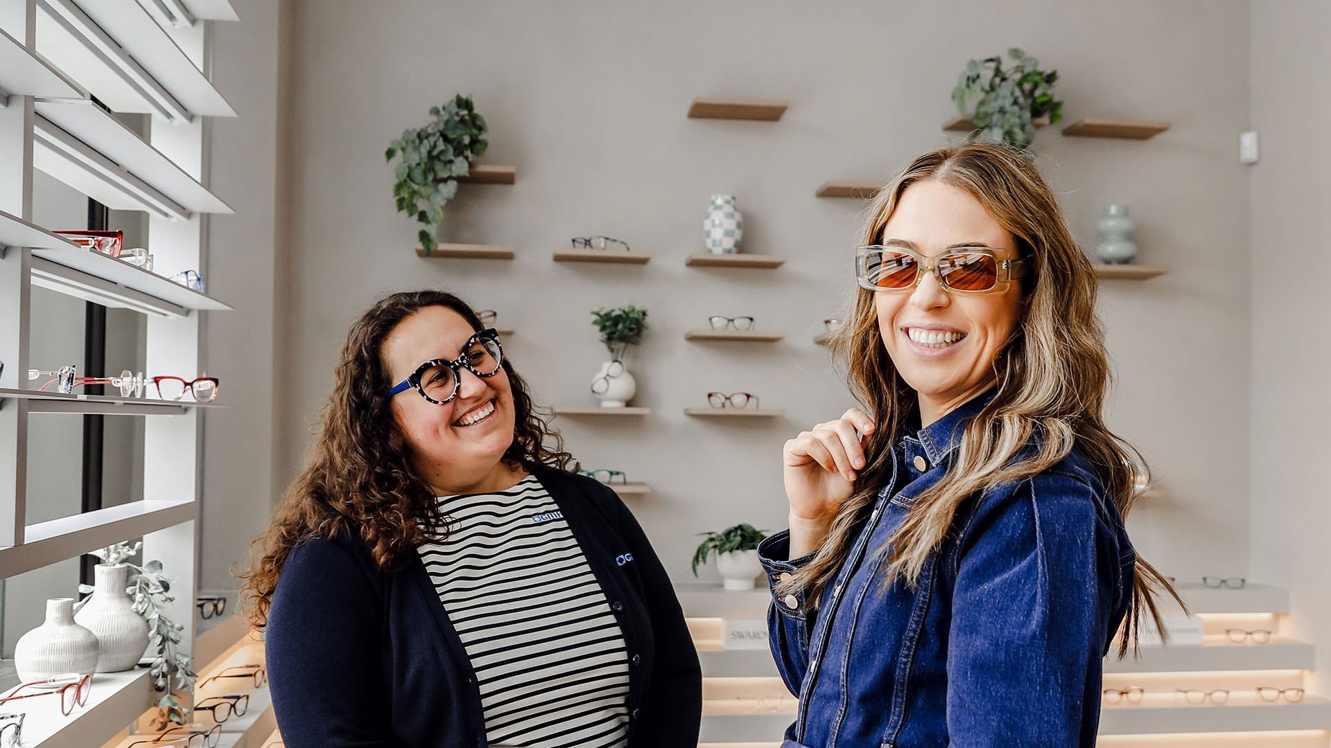 Customer visiting GMHBA Eye Care trying on a new pair of green glasses