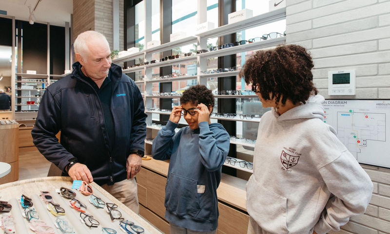 Young child trying on prescription frames with GMHBA Eye Care optometrist.