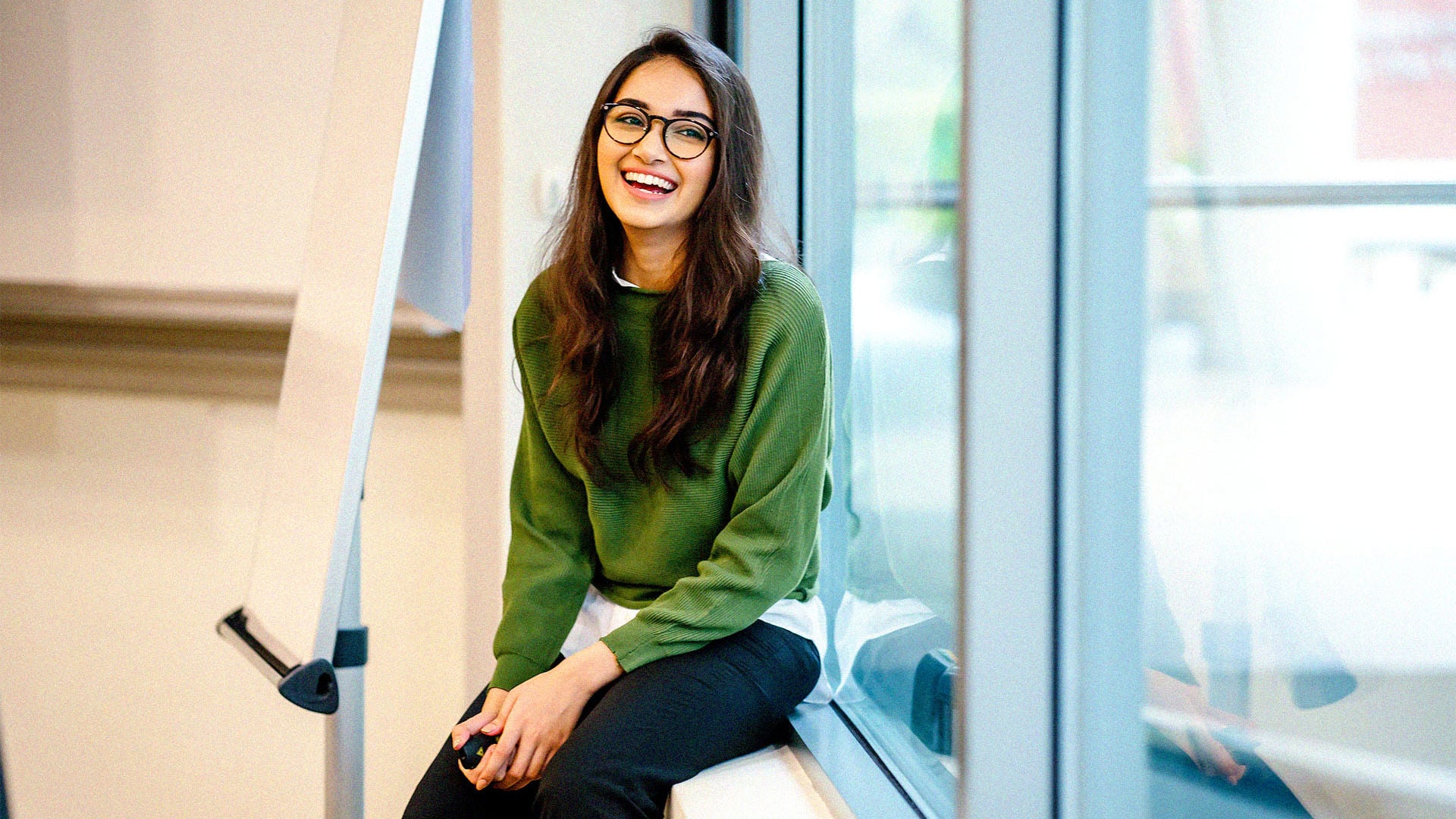 Young lady attending class smiling at her peers while at university