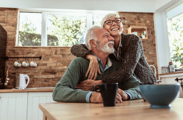Old couple cuddling in the kitchen enjoying their health with support of GMHBA