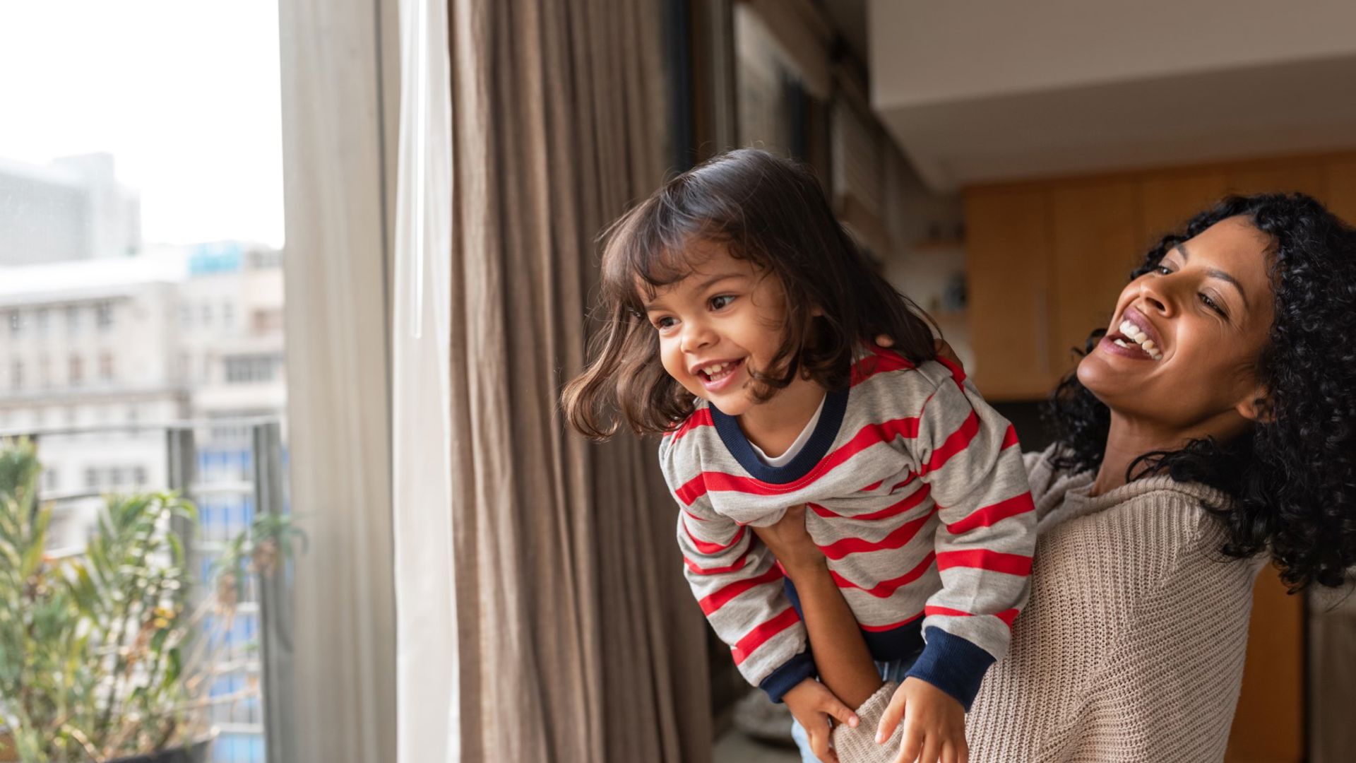 A mother and daughter playing near a window.