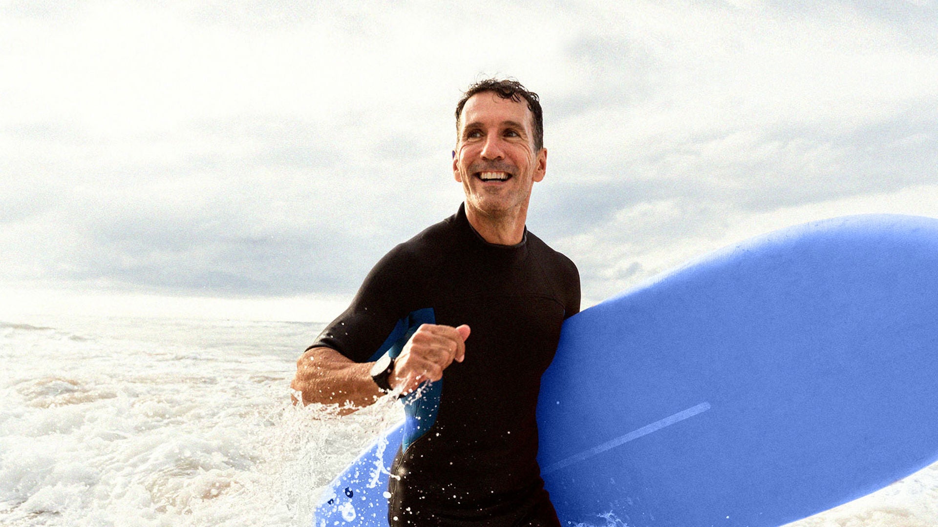 Middle aged male enjoying a surf with a blue surfboard