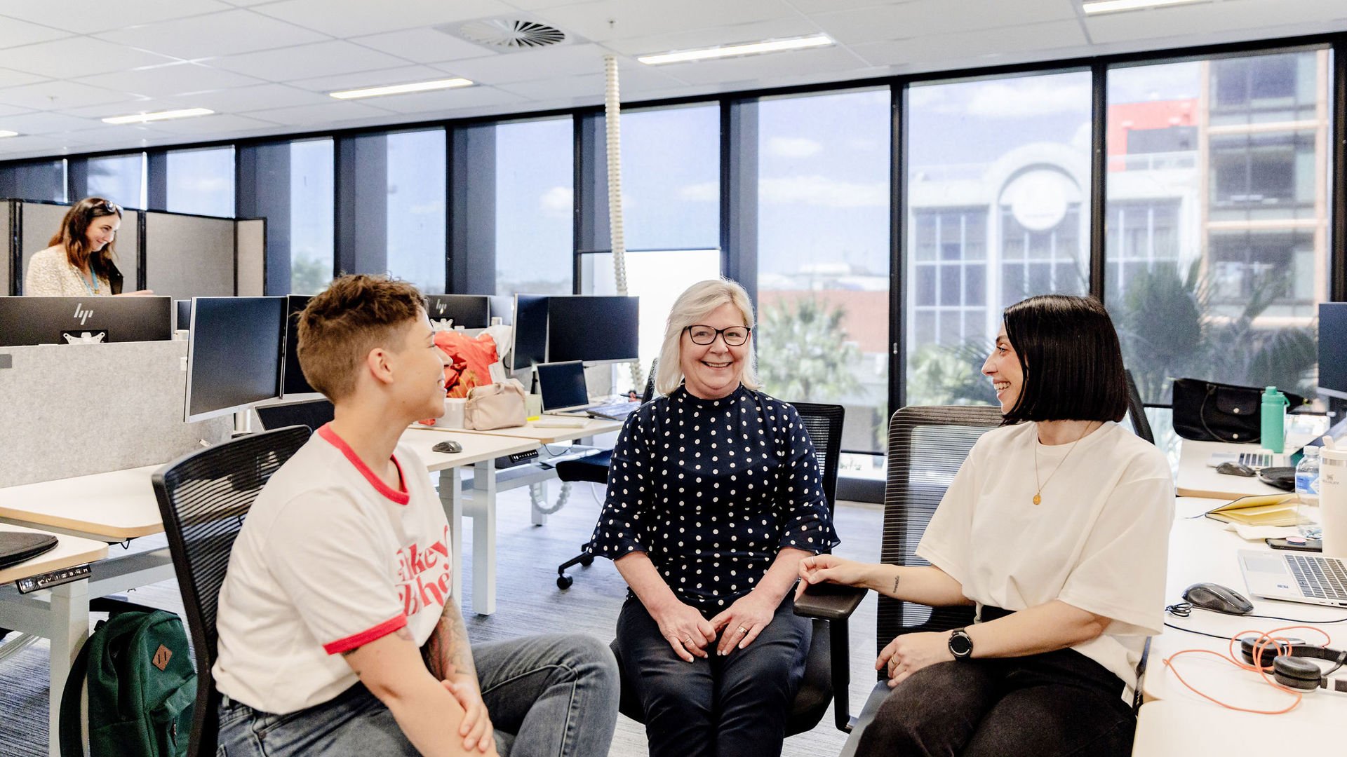 Three GMHBA Staff members happily chatting in light filled open office space
