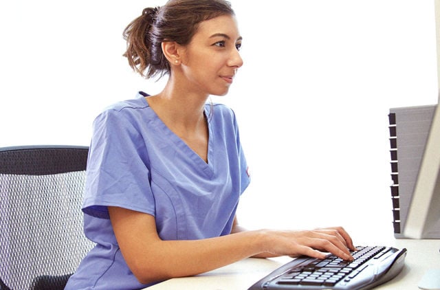 Nurse in scrubs using a computer